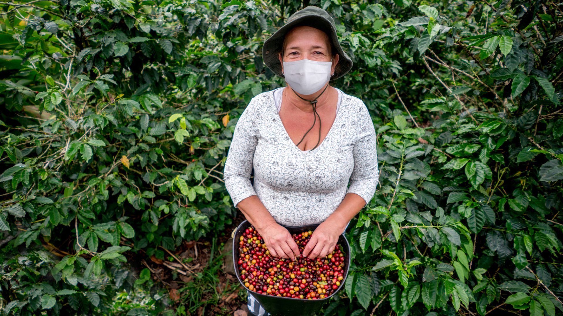 Mulher usando máscara em plantação de café