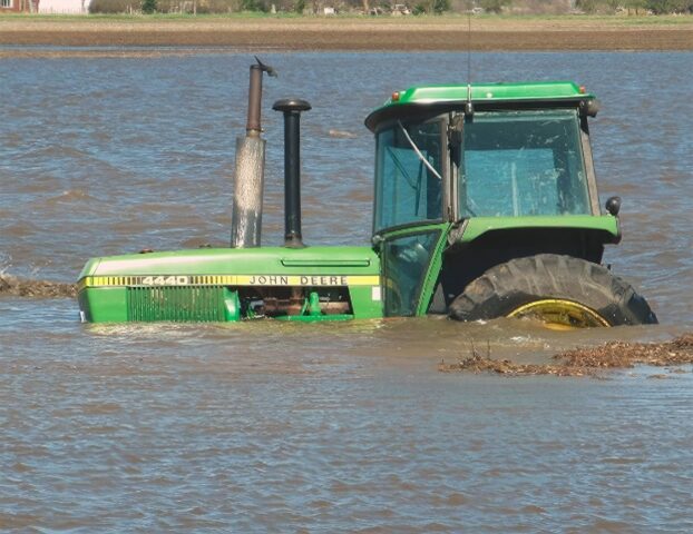 máquina agrícola no meio da enchente, cuja metade está dentro d'água